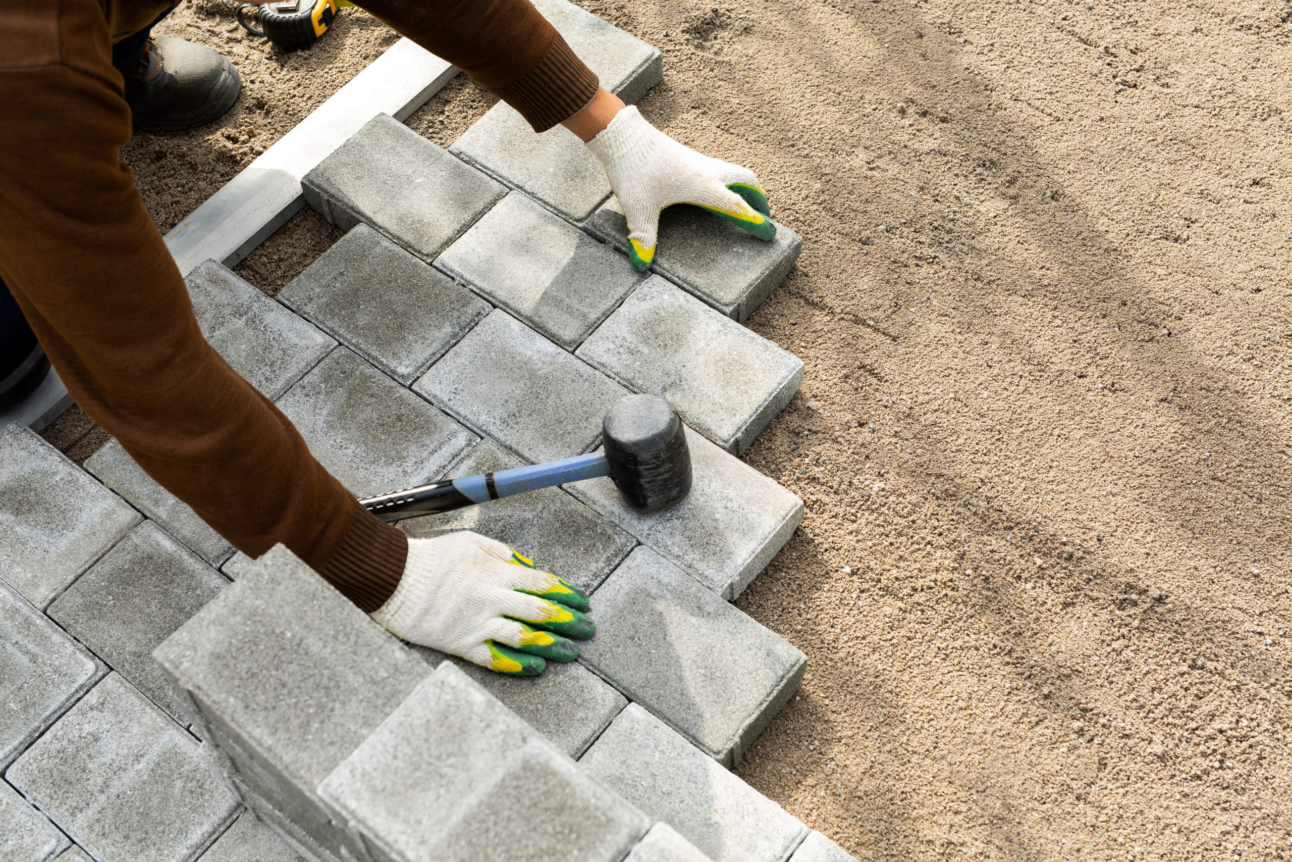 hands-worker-installing-concrete-blocks-paving-slabs-with-rubber-hammer